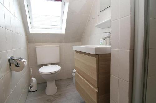 ein Bad mit einem WC, einem Waschbecken und einem Fenster in der Unterkunft Haus Schumacher, Wohnung 1 in Hörnum