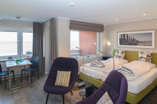 um quarto de hotel com uma cama, uma secretária e cadeiras em bi Strön em Hörnum