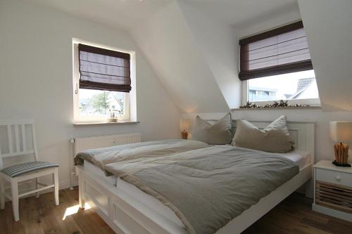 a white bedroom with a bed and two windows at Seaside 4 in Hörnum