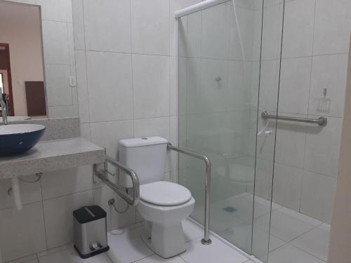 a bathroom with a toilet and a glass shower at Pousada Receptur in Piranhas