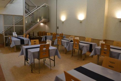 una sala da pranzo con tavoli, sedie e una scala di HOTEL LiVEMAX BUDGET SAPPORO a Sapporo