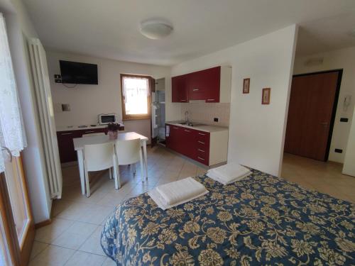 a bedroom with a bed and a kitchen with a table at Residenza Arcobaleno in Tenno
