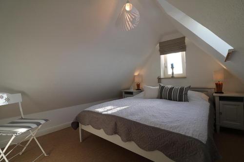 ein Schlafzimmer mit einem Bett und einem Stuhl im Dachgeschoss in der Unterkunft Südspitze 01 in Hörnum