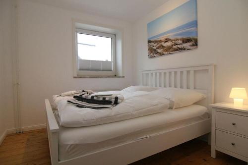 ein weißes Bett in einem Schlafzimmer mit einem Fenster in der Unterkunft Ferienhaus TerpMeren in Hörnum