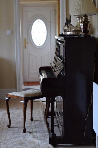a piano in a living room with a window at Corner House in Newport