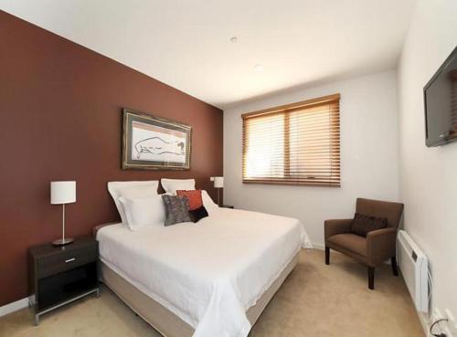 a bedroom with a large white bed and a chair at Brighton Bay Apartments in Melbourne