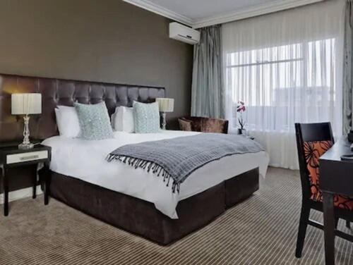 Ascot Hotel في جوهانسبرغ: غرفة نوم كبيرة مع سرير كبير ونافذة