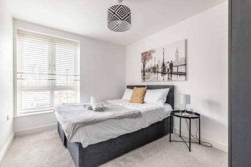 a bedroom with a bed in a white room at 2 BED & 2 BATH COSY APARTMENT SLOUGH- FREE PARKING in Slough