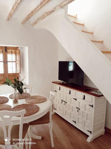 a dining room with a white table and a tv at La Casita Tipica in Zuheros