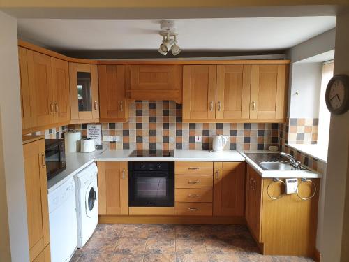 a kitchen with wooden cabinets and white appliances at Kesh self catering holiday home. in Kesh