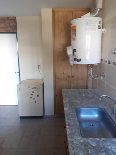 a kitchen with a sink and a refrigerator at Cabaña Namasté in Huerta Grande