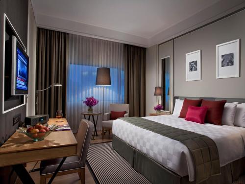 a hotel room with a large bed and a desk with a table at Orchard Hotel Singapore in Singapore