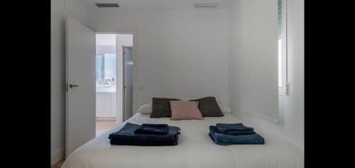 Una cama blanca con dos toallas azules. en Atico de Lujo en Valencia