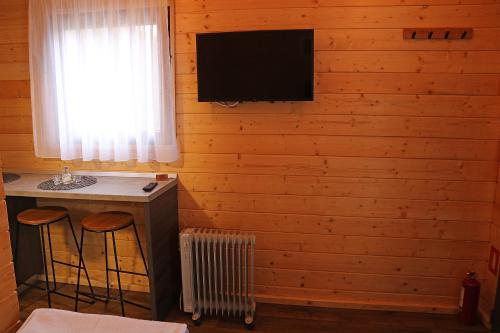 Habitación con escritorio y TV en la pared. en Cabanute Premium de pescuit en Sînmărghita