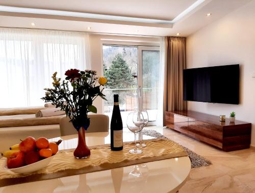 ein Wohnzimmer mit einem Tisch und einer Flasche Wein in der Unterkunft Nobless Apartments Holedná Brno in Brünn