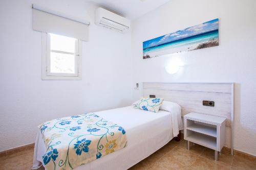 a white bedroom with a bed and a window at Sol y Mar in Playa Migjorn