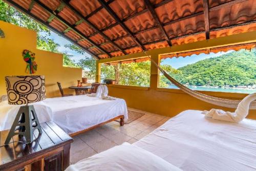 1 dormitorio con 2 camas y hamaca. en Casas Garcia, en Yelapa