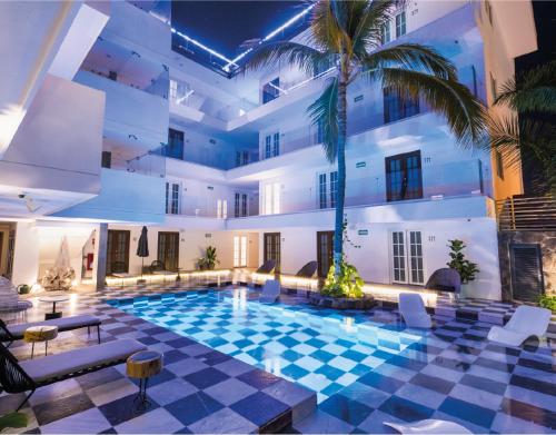 a swimming pool in a building with a palm tree at The Xperience by g in Mazatlán