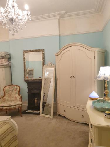 a room with a cabinet and a mirror and a chair at Judy's B&B private home in Cardiff