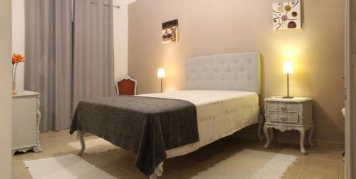 a bedroom with a bed and a nightstand with two lamps at Casa Luz in Vila Nova de Milfontes