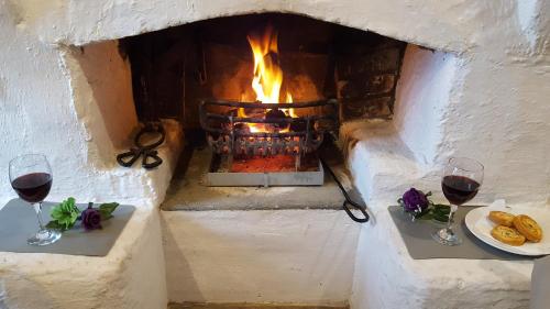 two glasses of wine in front of a fireplace at Donegal Thatched Cottage in Loughanure