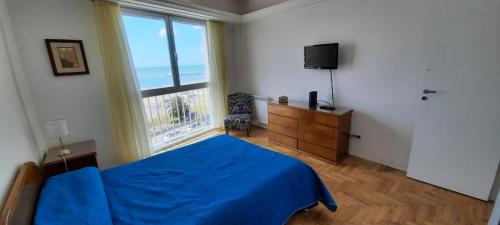 1 dormitorio con cama azul y ventana grande en ALMAR III Sólo para familias en Mar del Plata