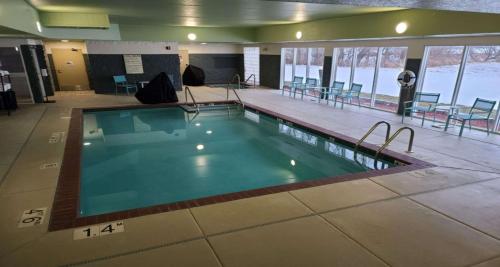 a large swimming pool in a building with tables and chairs at Best Western Watertown in Watertown