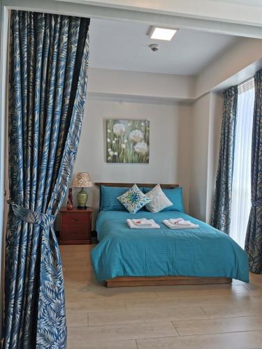 a bedroom with a blue bed and curtains at Mactan Newtown Deluxe Island Breeze in Mactan