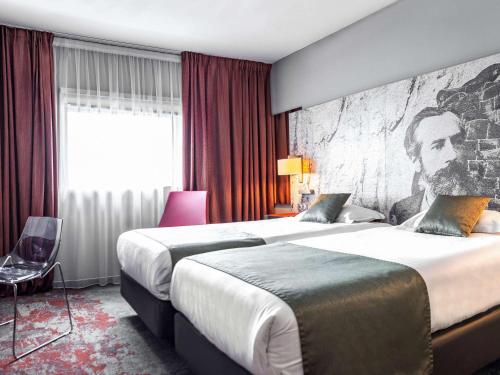 a hotel room with two beds and a painting of a man at Mercure Belfort Centre in Belfort