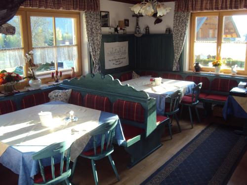 un restaurante con 2 mesas, sillas y ventanas en Neumaierhof, en Haus im Ennstal