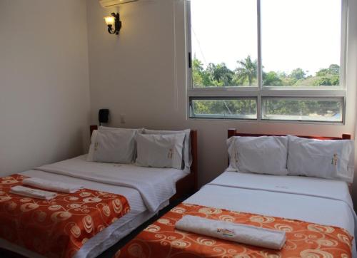 two beds in a room with two windows at Hotel Rio Humadea in Guamal