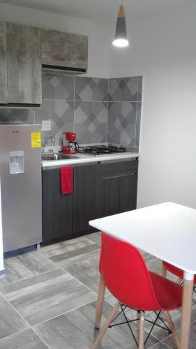 a kitchen with a white table and a red chair at HospedArte Loreto in Loreto
