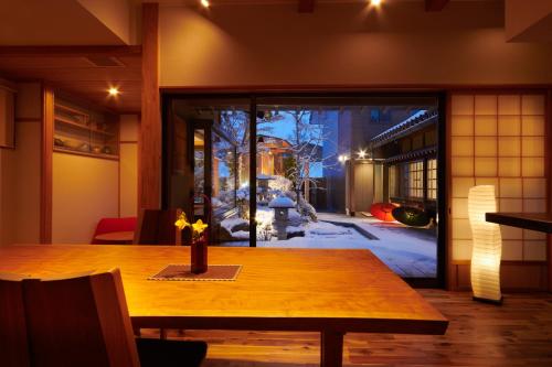 een eetkamer met een houten tafel en een raam bij Ichinomatsu Japanese Modern Hotel in Takayama