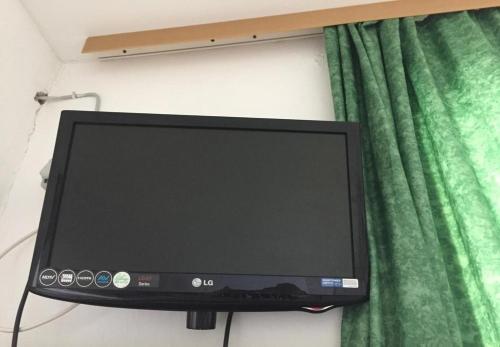 a computer monitor on a wall next to a green curtain at Apartment Ivica in Sućuraj
