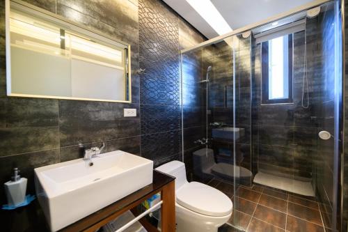 ein Bad mit einem Waschbecken, einem WC und einer Dusche in der Unterkunft 澎湖遛一遛旅店 in Magong