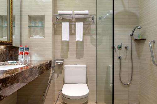 a bathroom with a toilet and a glass shower at Hotel Santika Bandung in Bandung