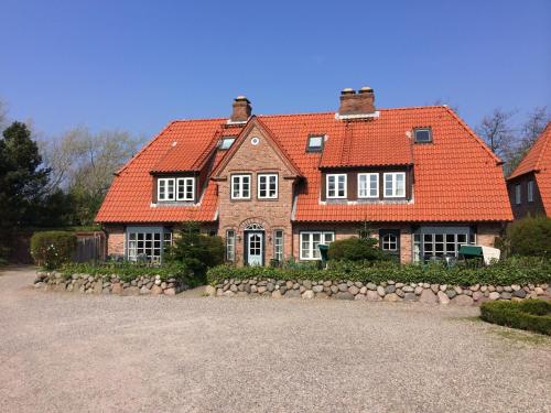 a large brick house with an orange roof at Ferienhäuser im Sylter Gartenweg in Tinnum