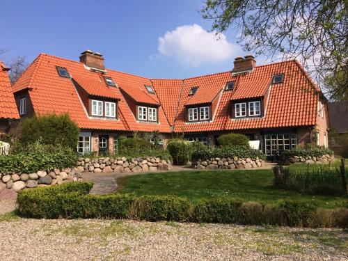 ein großes Haus mit orangefarbenem Dach in der Unterkunft Ferienhäuser im Sylter Gartenweg in Tinnum