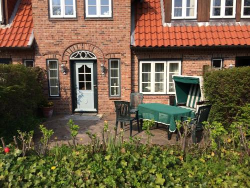 a house with a green table and chairs in the yard at Ferienhäuser im Sylter Gartenweg in Tinnum