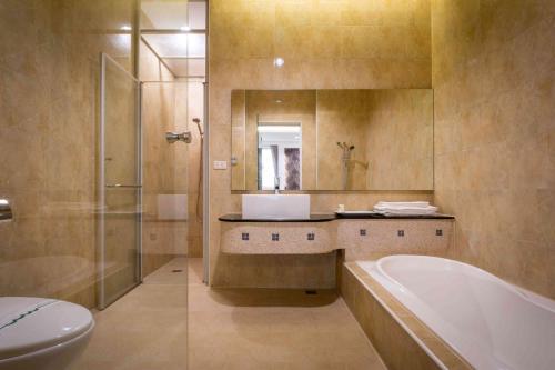 a bathroom with a tub and a sink and a toilet at Alegran Motel in Wuqi