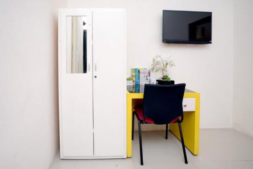 Zimmer mit einem Schreibtisch, einem Stuhl und einem TV in der Unterkunft DPARAGON PAMELA 4 in Yogyakarta