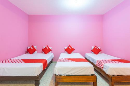 two twin beds in a room with pink walls at OYO Hotel Emperador, Oaxaca in Oaxaca City