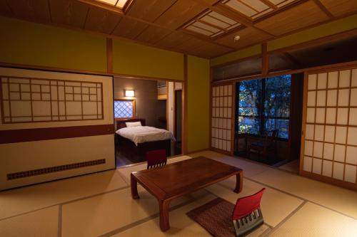a room with a bedroom with a bed and a table at Baien in Yufuin