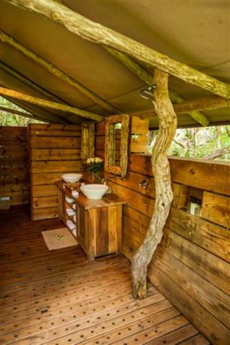 a bathroom in a log cabin with a tree branch at Summerfields Rose Retreat and Spa in Hazyview