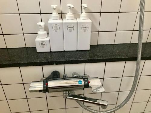 a shelf with four bottles on a bathroom wall at 民泊ありんくりん in Haebaru