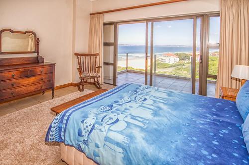 a bedroom with a blue bed and a view of the ocean at Beach Music I and II in Keurboomstrand