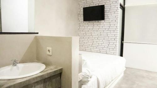 Un baño con un lavabo blanco y una pared de ladrillo. en DPARAGON BEO, en Yogyakarta