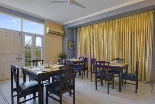 a dining room with tables and chairs and a window at Shahpura Dev Villa in Udaipur