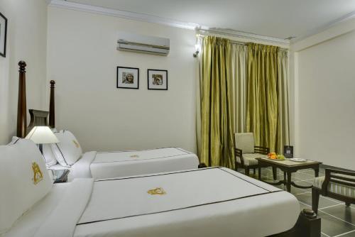 a hotel room with two beds and a table at Shahpura Dev Villa in Udaipur