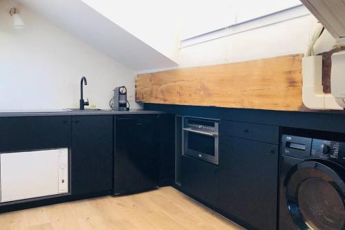 - une cuisine avec des armoires noires et un lave-linge dans l'établissement Studio vue mer dans le quartier de saint Victor, à Marseille